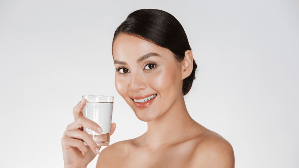 Woman with hydrated skin holding a glass of water.